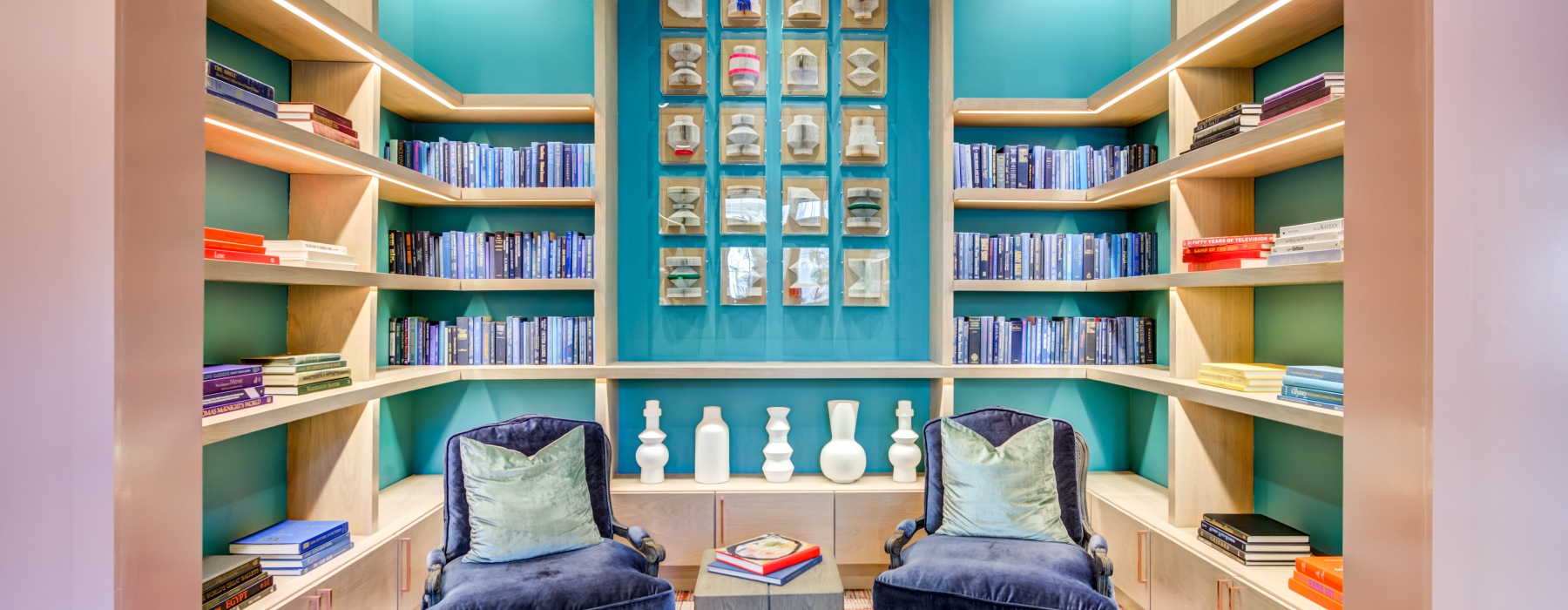 Cozy sitting area with two chairs surrounded by shelves of books at The Margo new apartments in Frisco, TX